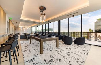 a pool table and chairs in a room with floor to ceiling windows